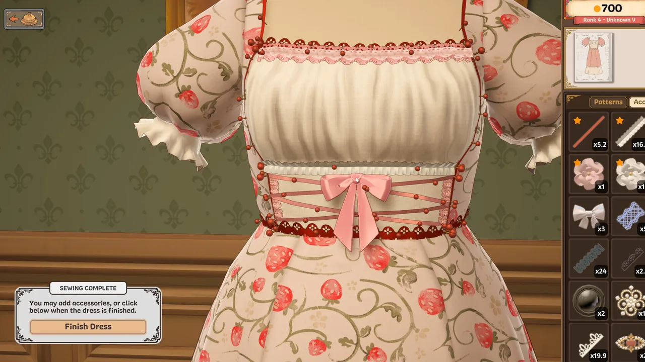 Close-up of a finished strawberry-print dress with a pink bow and accessory tray